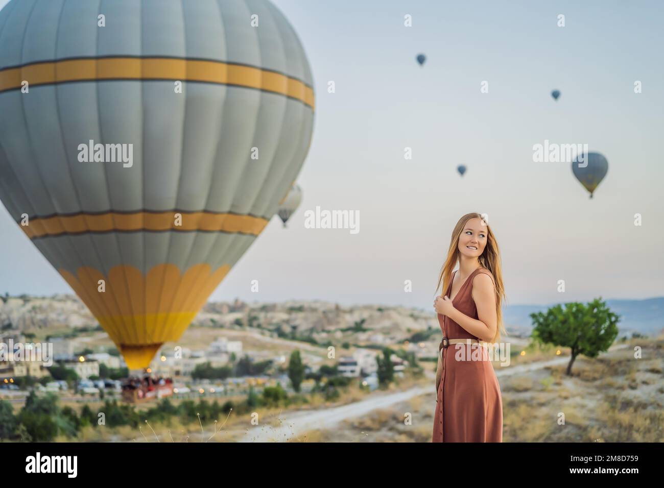 Eine Touristin, die Heißluftballons in Kappadokien, Türkei, ansieht. Happy Travel in Turkey Concept. Eine Frau auf einem Berggipfel, die eine wunderbare Aussicht genießt Stockfoto