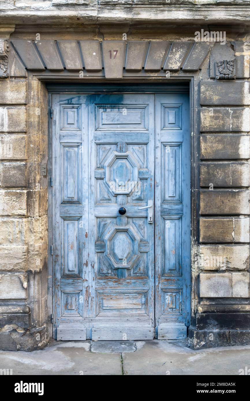 Blaue Holztür mit abblätternder Farbe in einer Steinwand, außen Stockfoto