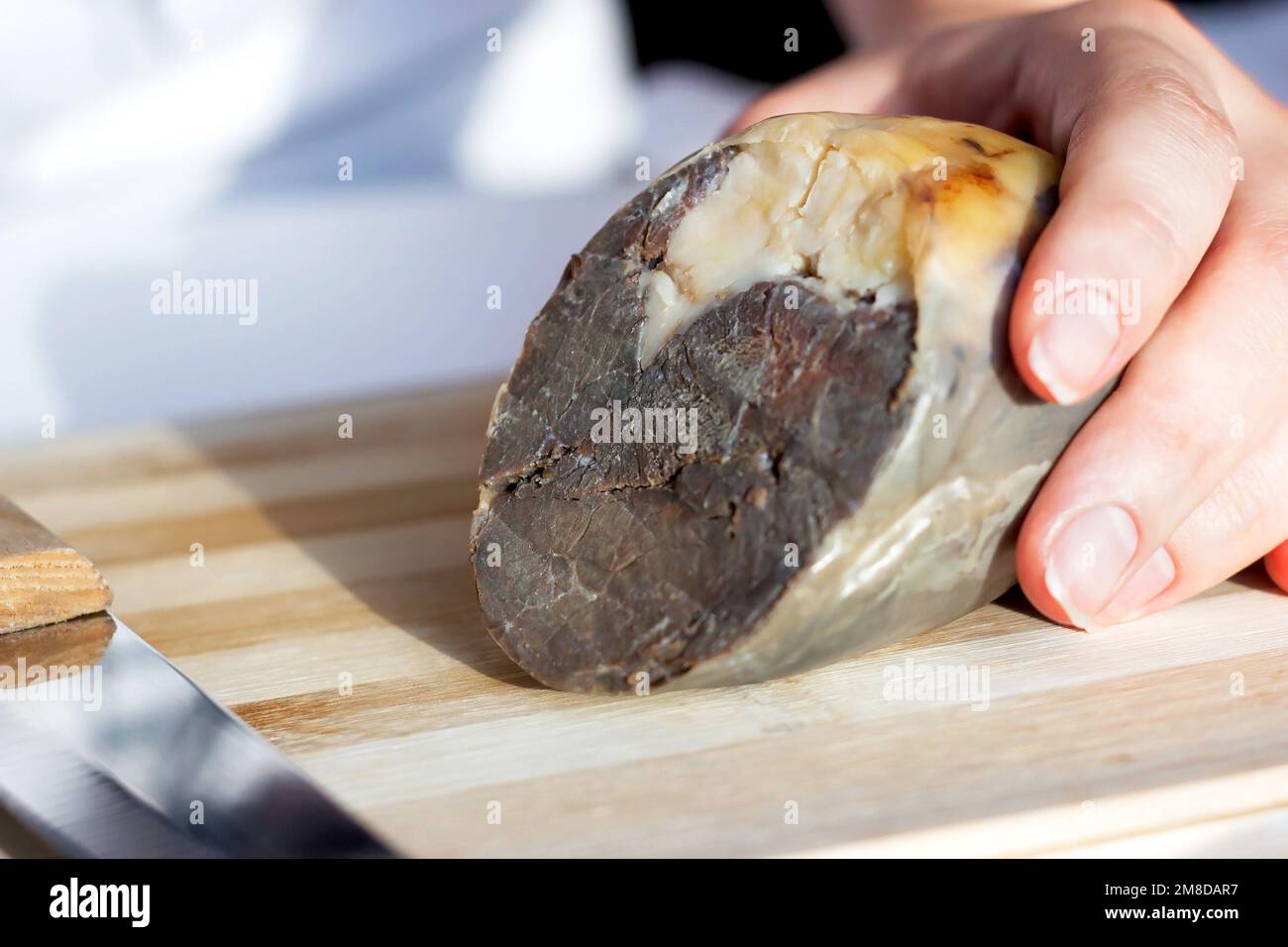 Die traditionelle kasachische Pferdefleischwurst Kazy auf dem hölzernen Schneidebrett aus nächster Nähe. Stockfoto