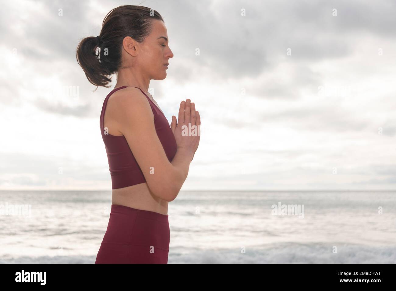 Frau betet und meditiert draußen am Meer. Selbstfürsorge und Achtsamkeit, Menthalgesundheit. Aufwachen am Morgen. Stockfoto