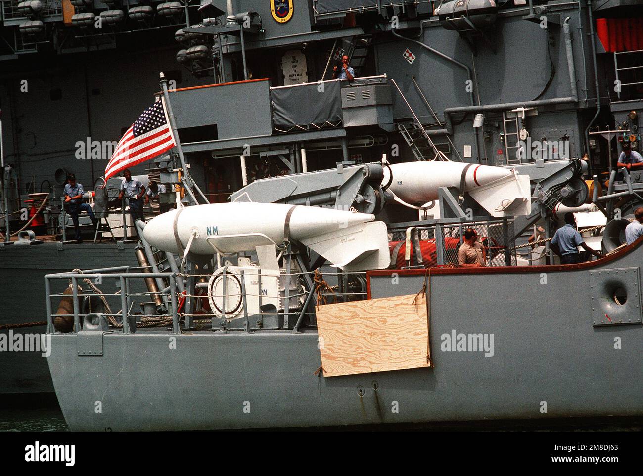 Besatzungsmitglieder stehen auf dem Heck der USS AVENGER (MCM-1) bereit, während Vorbereitungen für das Verladen des Minenabwehrschiffs an Bord des holländischen Schwertransportschiff SUPER SERVANT 3 getroffen werden. Der SUPERDIENER 3 wird AVENGER und andere Minenräumer in den Persischen Golf transportieren, als Reaktion auf die Invasion Kuwaits durch den Irak. Betreff Betrieb/Serie: WÜSTENSCHILD/STURMSTÜTZPUNKT: Marineflugstation, Norfolk Bundesstaat: Virginia (VA) Land: Vereinigte Staaten von Amerika (USA) Stockfoto