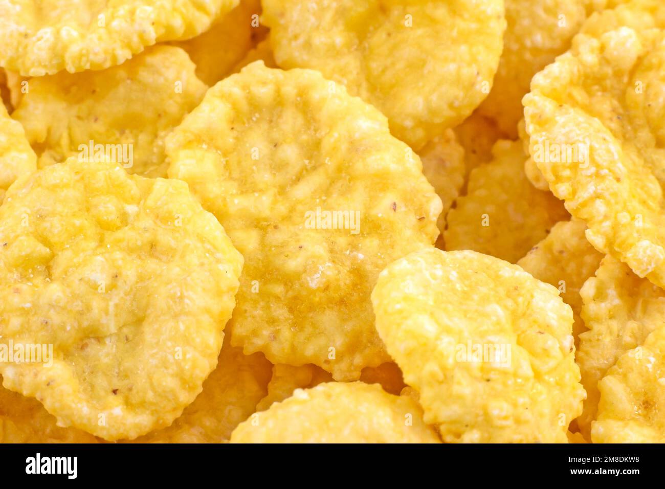Leuchtend gelbe leckere zuckerknusprige Cornflakes zum Frühstück als Nahaufnahme der Textur. Stockfoto
