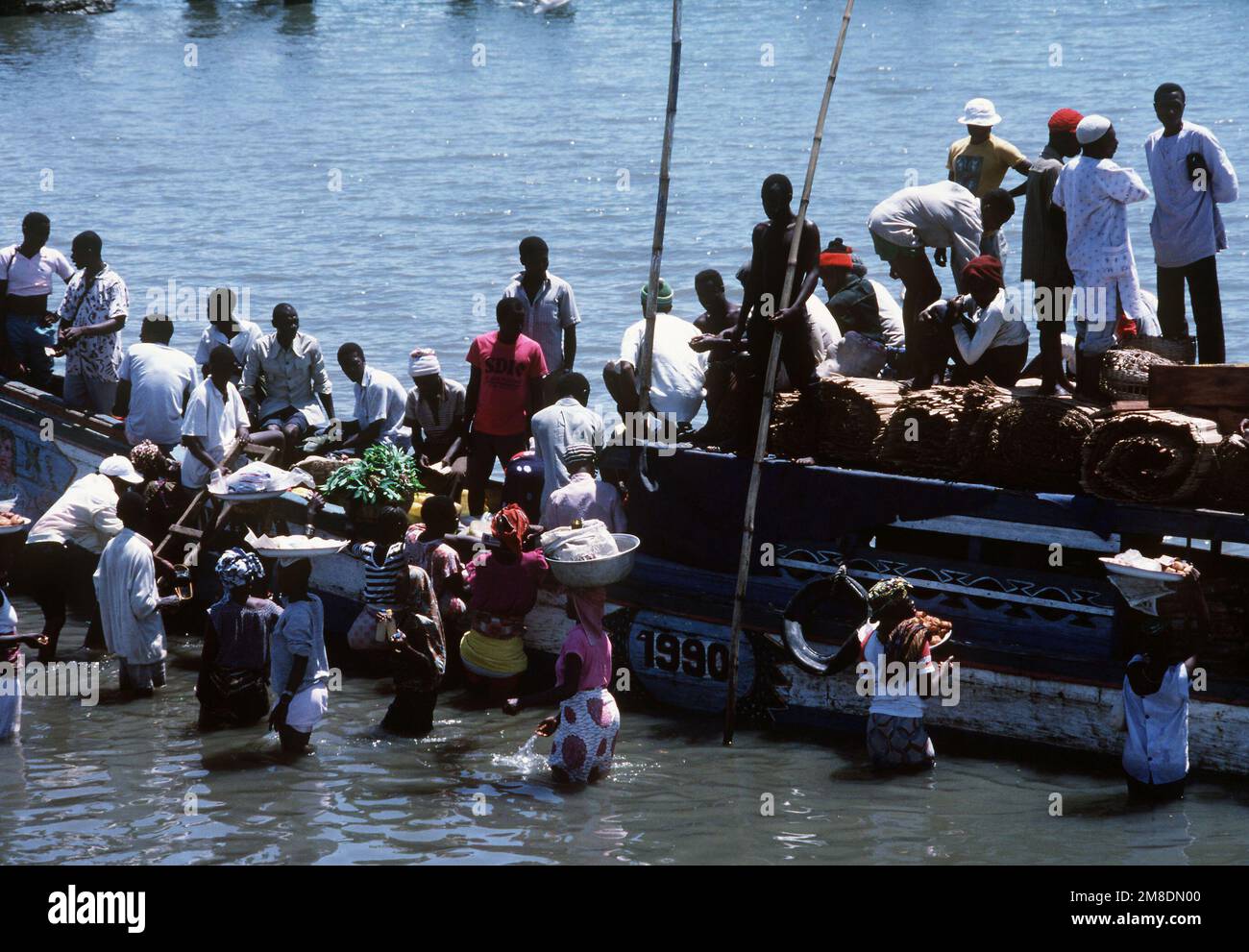 Die Einheimischen waten ins Wasser, um an Bord einer Fähre zu gehen. Lungi befindet sich nördlich von Freetown, Sierra Leone, und ist ein Clearingpunkt für Zivilisten, die im Rahmen der Operation Sharp Edge aus Liberia evakuiert wurden. Betreff Betrieb/Serie: SCHARFE KANTE Basis: Lungi Country: Sierra Leone (SLE) Stockfoto