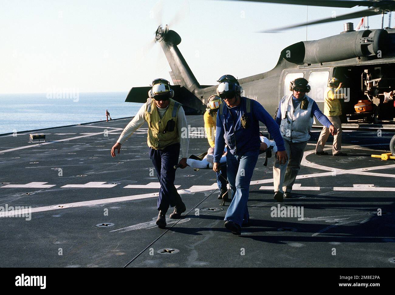 Matrosen tragen einen Wurfpatienten über das Flugdeck des Krankenhausschiffs USNS MERCY (T-AH-19), nachdem sie ihn aus einem Army UH-60A Black Hawk (Blackhawk) Helikopter entfernt haben. Die GNADE wird im Golf eingesetzt, um Operation Desert Shield zu unterstützen. Betroffene Operation/Serie: WÜSTENSCHILD Land: Unbekannt Stockfoto