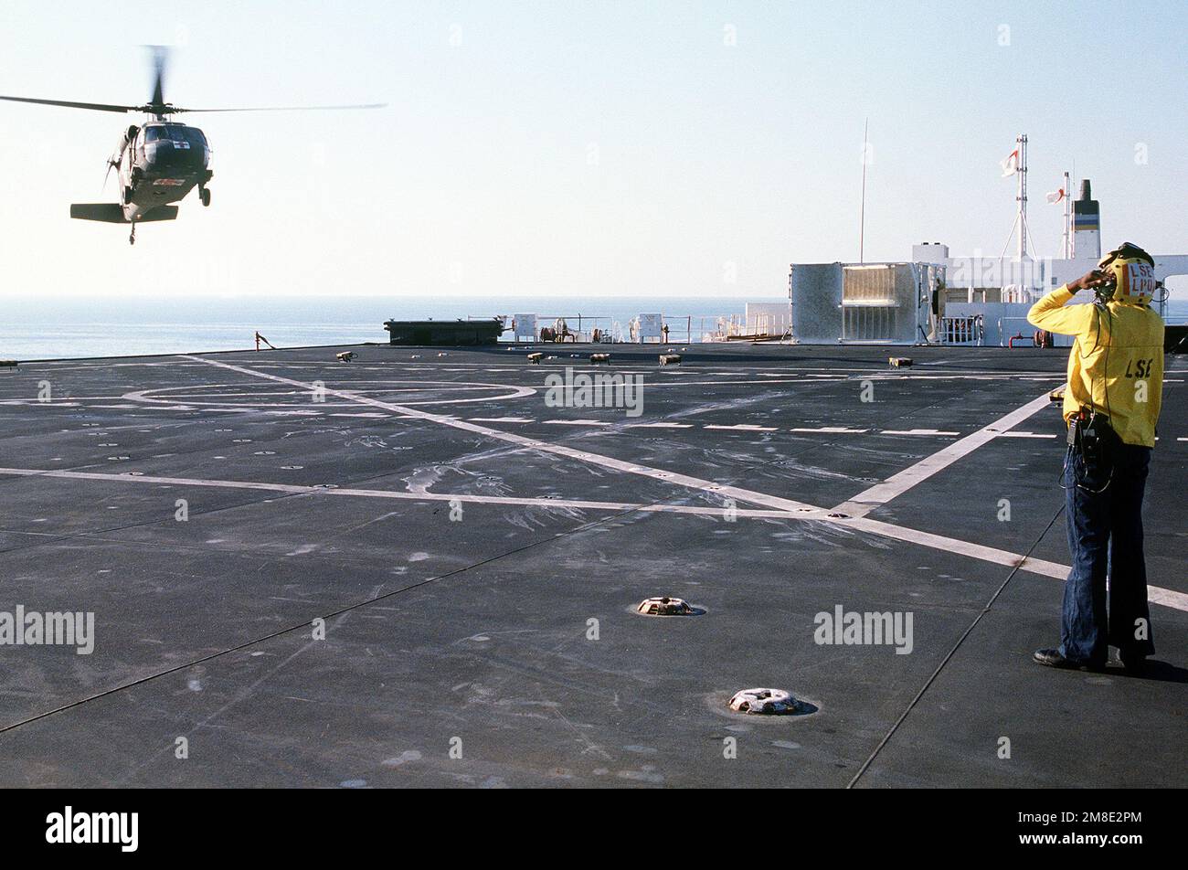 Ein Landesignal Enlisted man (LSE) an Bord des Krankenhausschiffs USNS MERCY (T-AH-19) leitet einen Army UH-60A Black Hawk (Blackhawk) Helikopter zur Landung auf dem Flugdeck des Schiffs. Die GNADE wird im Golf eingesetzt, um Operation Desert Shield zu unterstützen. Betroffene Operation/Serie: WÜSTENSCHILD Land: Unbekannt Stockfoto