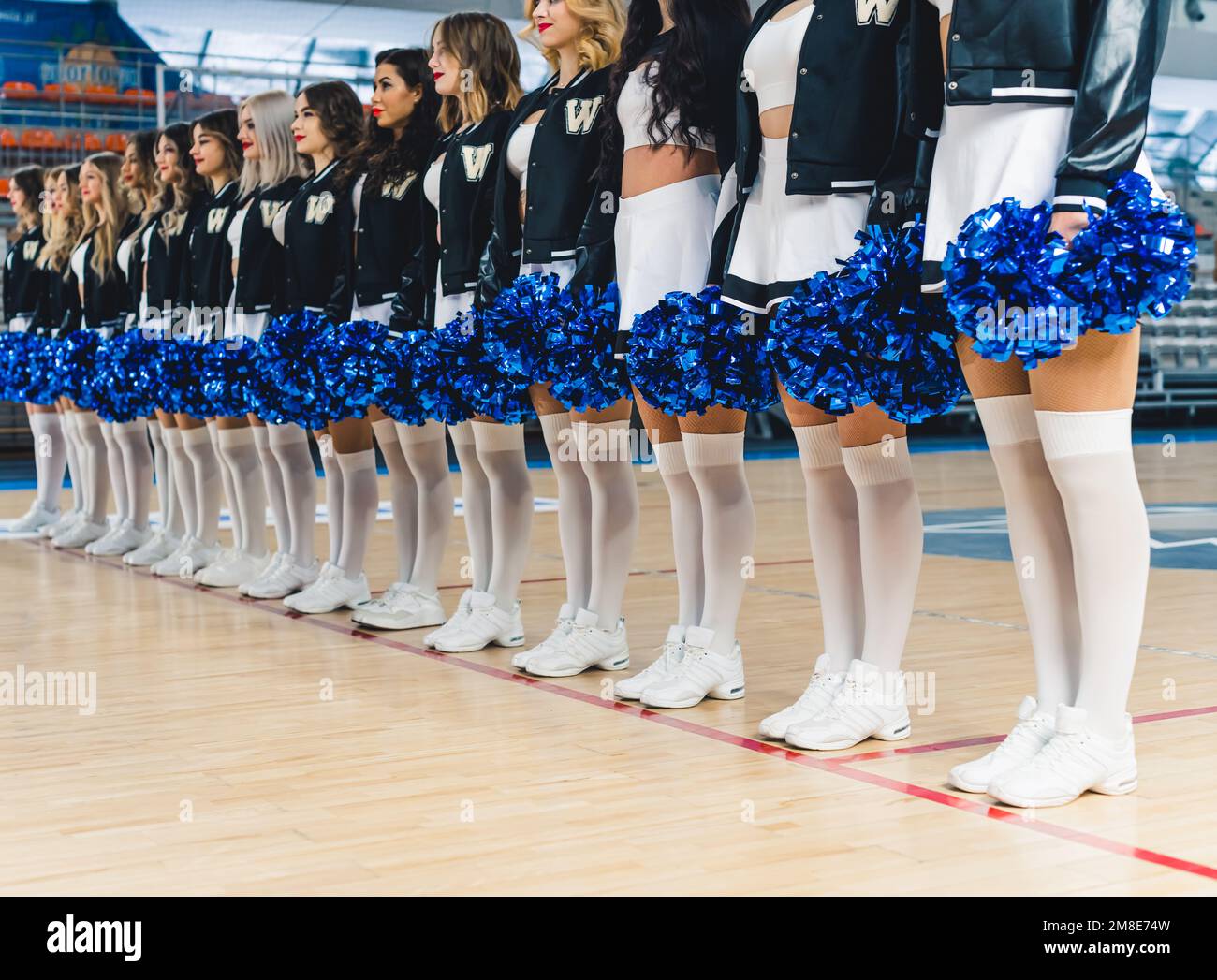 Cheerleader in Miniröcken und kniehohen Socken, die Pom-Poms halten, konzentrieren sich auf ihre Beine. Stockfoto