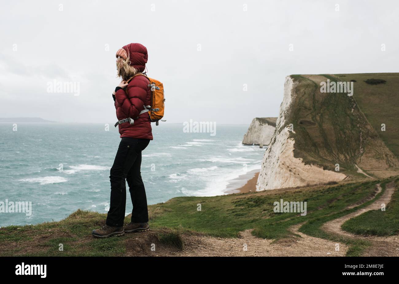 Eine Frau, die am Rande der Jurassic Coast in Dorset England steht Stockfoto