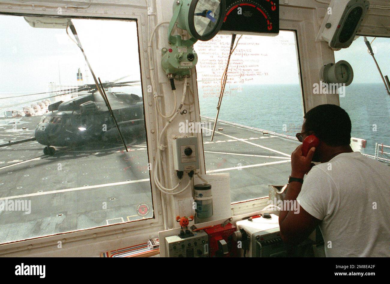 Ein Fluglotse kommuniziert mit dem Piloten eines Helicopter Combat Support Squadron 1 (HC-1) CH-53E Super Hallion Helikopters, wenn er für den Start vom Flugdeck des Krankenhausschiffs USNS COMFORT (T-AH-20) vorbereitet ist. Der KOMFORT wird während der Operation Desert Storm am Persischen Golf eingesetzt. Betroffene Operation/Serie: WÜSTENSTURM Land: Unbekannt Stockfoto