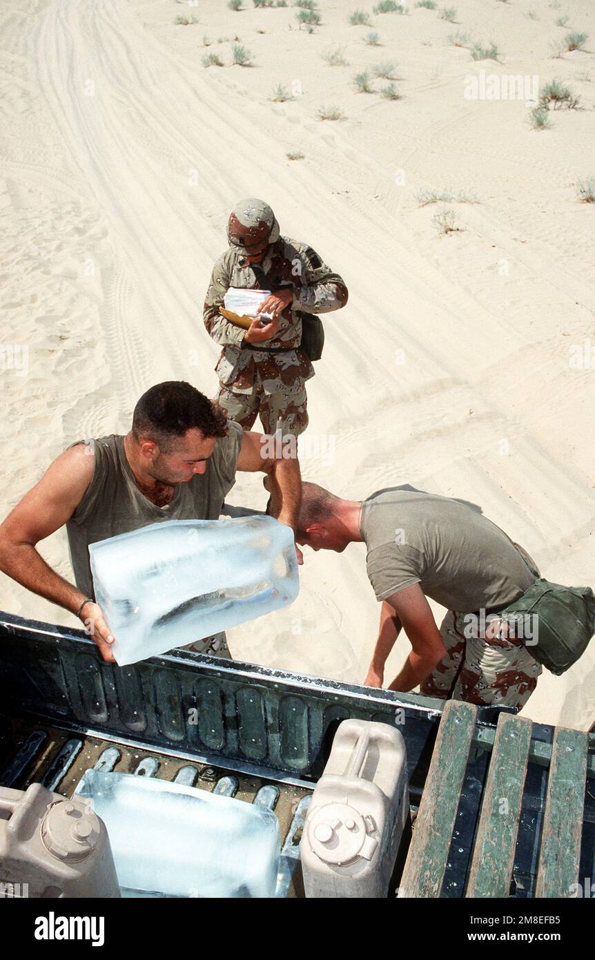 Zwei Soldaten der 82. Luftwaffe entladen einen Eisblock von einem Laster, während ein weiterer Soldat während der Operation Desert Shield nach der Post ihrer Einheit sucht. Betreff Operation/Serie: WÜSTENSCHILD Land: Saudi-Arabien (Sau) Stockfoto