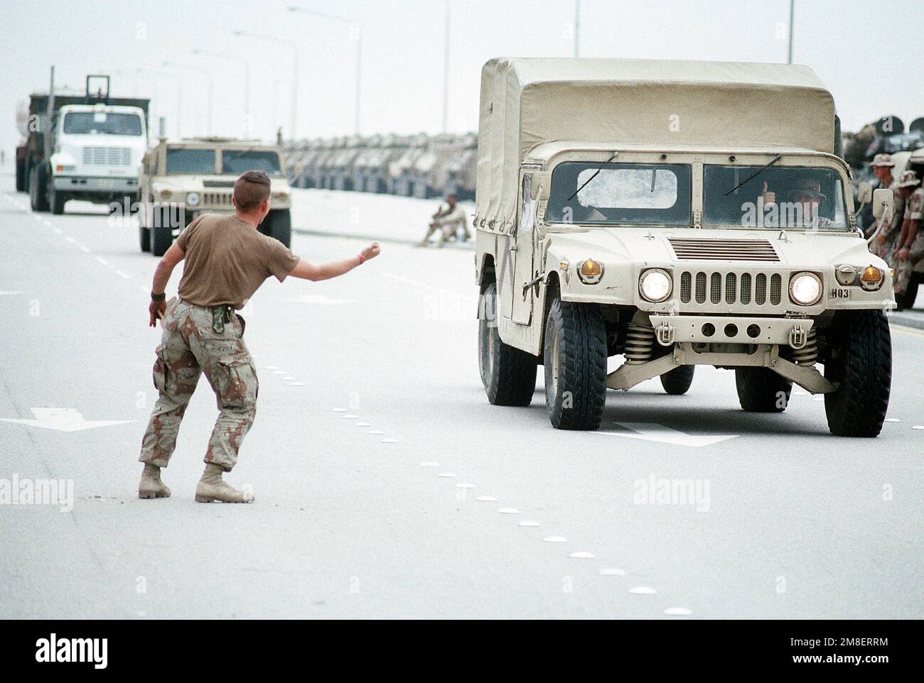 Ein Marine versucht scherzhaft, eine Fahrt mit einem M998 High-Mobility Multipurpose Wheeled Vehicle (HMMWV) anzuhalten, das nach Operation Desert Storm zum Pier für den Transport zurück in die USA gefahren wird. Betreff Operation/Serie: WÜSTENSCHILD WÜSTENSTURM Land: Saudi-Arabien (Sau) Stockfoto