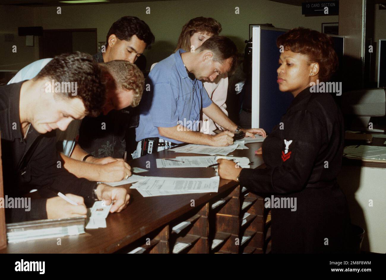 Ein Mitglied des Naval Reserve Readiness Command 20 (REDCOM-20), das die Einheit unterstützt, beobachtet, wie mehrere Reservisten der Marine Formulare ausfüllen. Die Reservisten sind gerade aus dem Dienst im Persischen Golf nach der Operation Desert Storm zurückgekehrt. Betreff Operation/Serie: WÜSTENSTURMBASIS: San Francisco Bundesstaat: Kalifornien (CA) Land: Vereinigte Staaten von Amerika (USA) Stockfoto