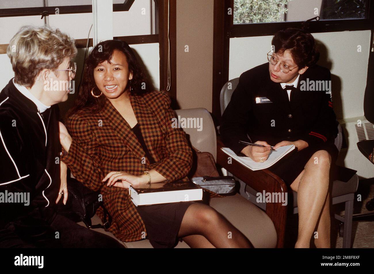 Die Ehefrauen von zwei Navy Reservisten werden von der Journalistin 2. Klasse Ofelia Chesney vom Naval Reserve Readiness Command 20 (REDCOM-20) interviewt, während die Frauen darauf warten, dass die Verarbeitung ihres Mannes abgeschlossen ist. Die Reservisten sind gerade aus dem Dienst im Persischen Golf nach der Operation Desert Storm zurückgekehrt. Betreff Operation/Serie: WÜSTENSTURMBASIS: San Francisco Bundesstaat: Kalifornien (CA) Land: Vereinigte Staaten von Amerika (USA) Stockfoto