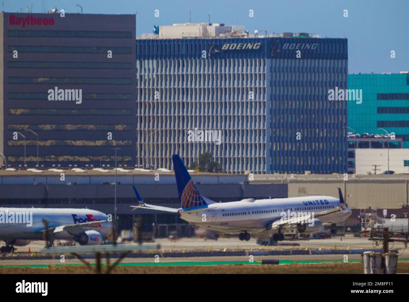 Detail vom Flughafen LAX in Los Angeles, Kalifornien, USA. Abbildung: FedEx- und United Airlines-Jets am LAX, mit Boeing- und Raytheon-Hauptsitz im Hintergrund. Stockfoto