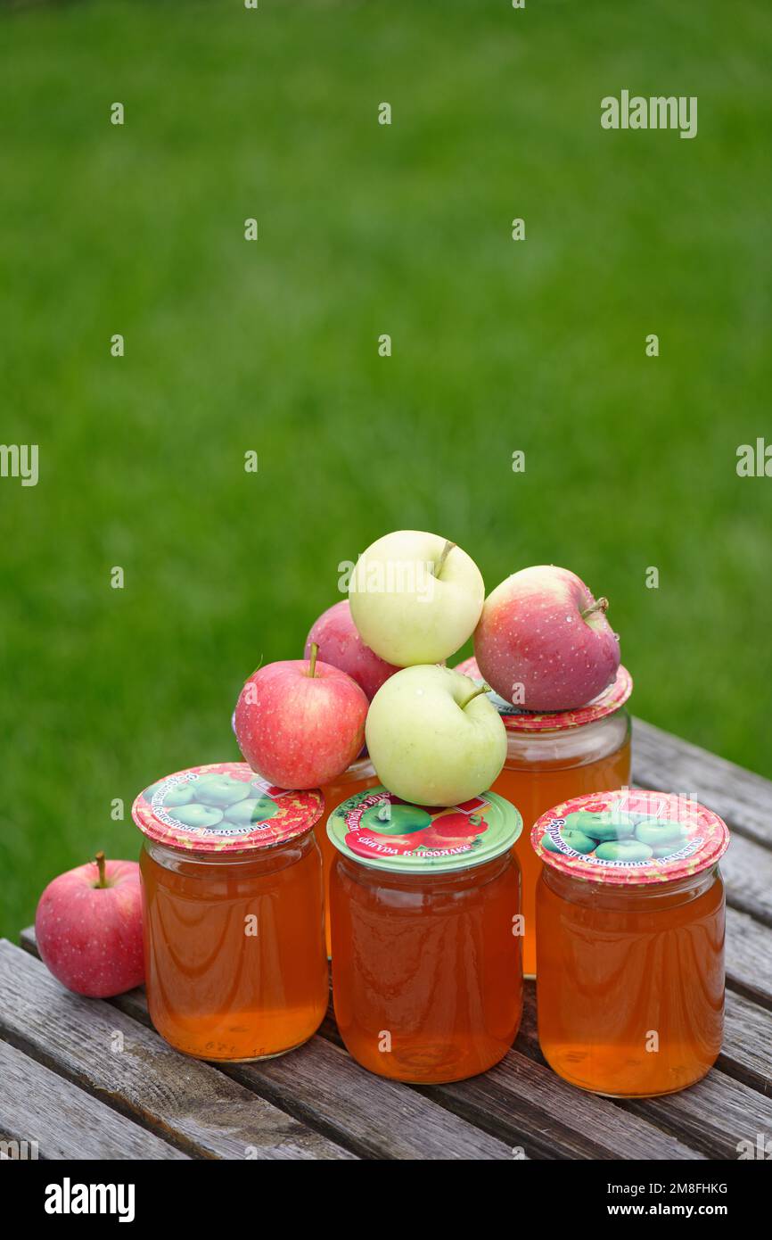 Frischer hausgemachter Apfelsaft in Glasgefäßen. Übersetzung russischer Aufschriften auf den Deckeln: „Rettung von Familienrezepten“ und „Gemüse aus dem Garten – Stockfoto