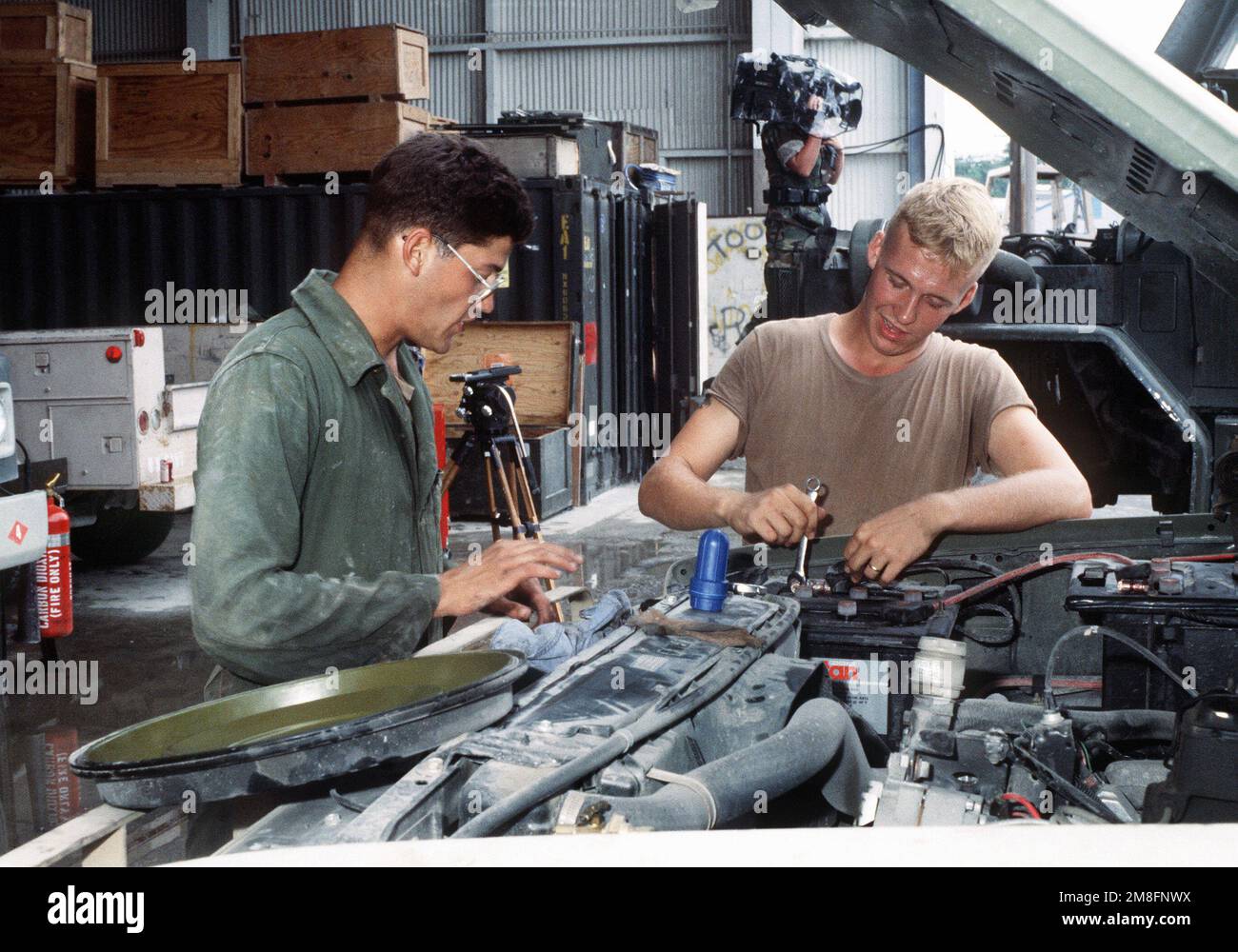 Zwei Seabees führen vorbeugende Wartungsarbeiten an einem Lkw durch, während ein Kamerad eines Navy-Fotografen andere Seabees bei der Arbeit im Hintergrund filmt. Mehrere Seabee Einheiten sind an der Flugstation, um bei der Säuberung der Vulkanasche zu helfen, die während des Ausbruchs des Mount Pinatubo fiel. Basis: Marineflugstation, Cubi Point Staat: Luzon Land: Philippinen (PHL) Stockfoto