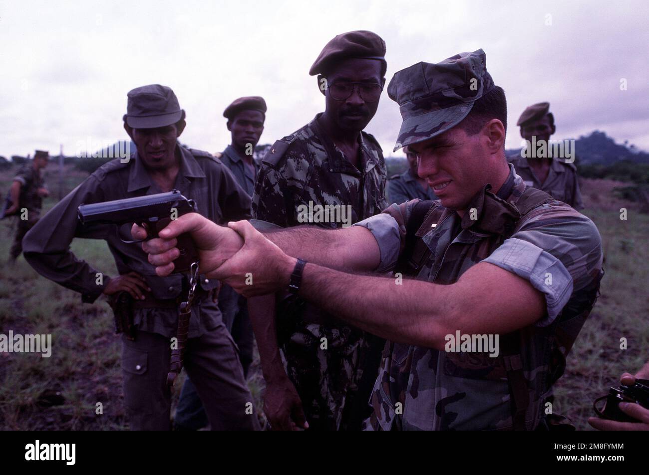 A. USA Der Marine vom Panzerlandeschiff USS BARNSTABLE COUNTY (LST-1197) zielt mit einer selbstladenden 9mm-mm-Makarov-Pistole, während westafrikanische Soldaten zusehen. Das BARNSTABLE COUNTY besucht westafrikanische Länder auf seiner Westafrikanische Trainingskreuzfahrt 1991. Land: Westafrika Stockfoto