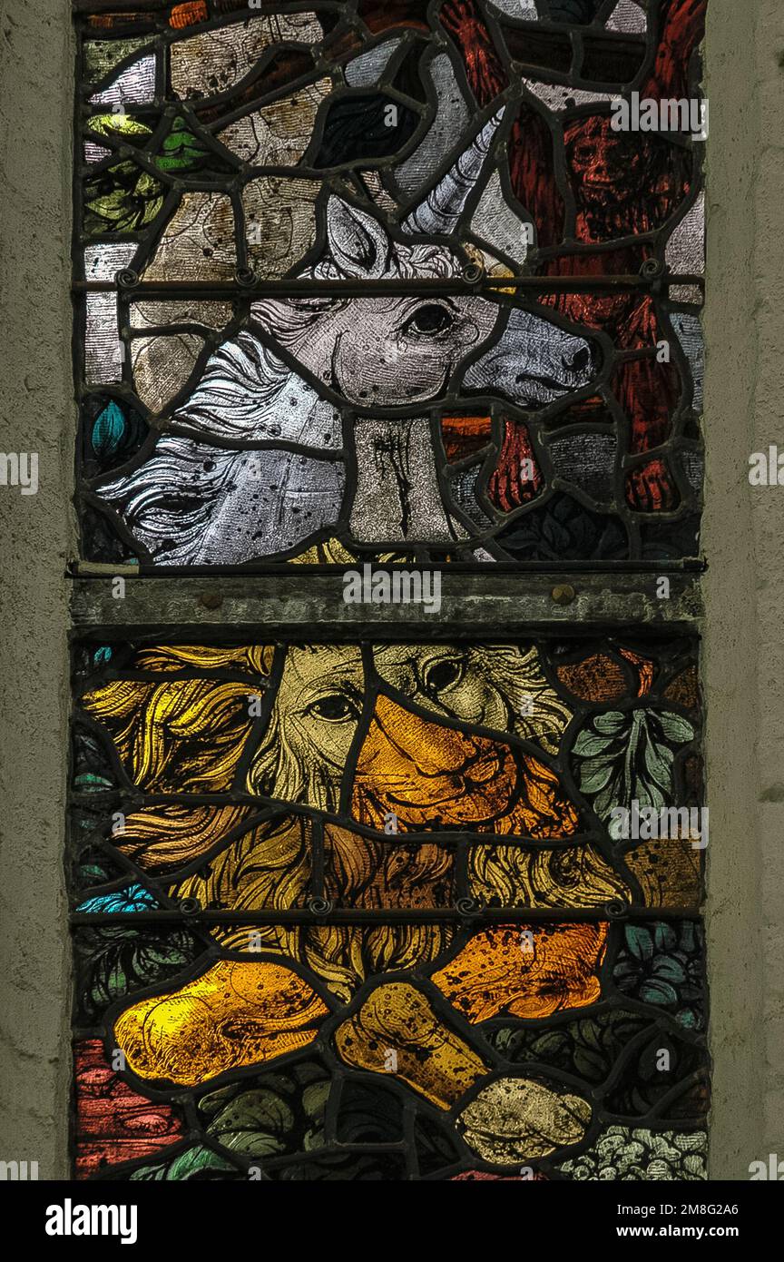 Goldener Löwe, weißes Einhorn und rötlicher Affe (oben rechts), an einem Baumzweig hängen. Mitte der 1900er Jahre Buntglas in einem Fenster der mittelalterlichen gotischen Oude Kerk oder der alten Kirche in Delft, Südholland, Niederlande. Stockfoto