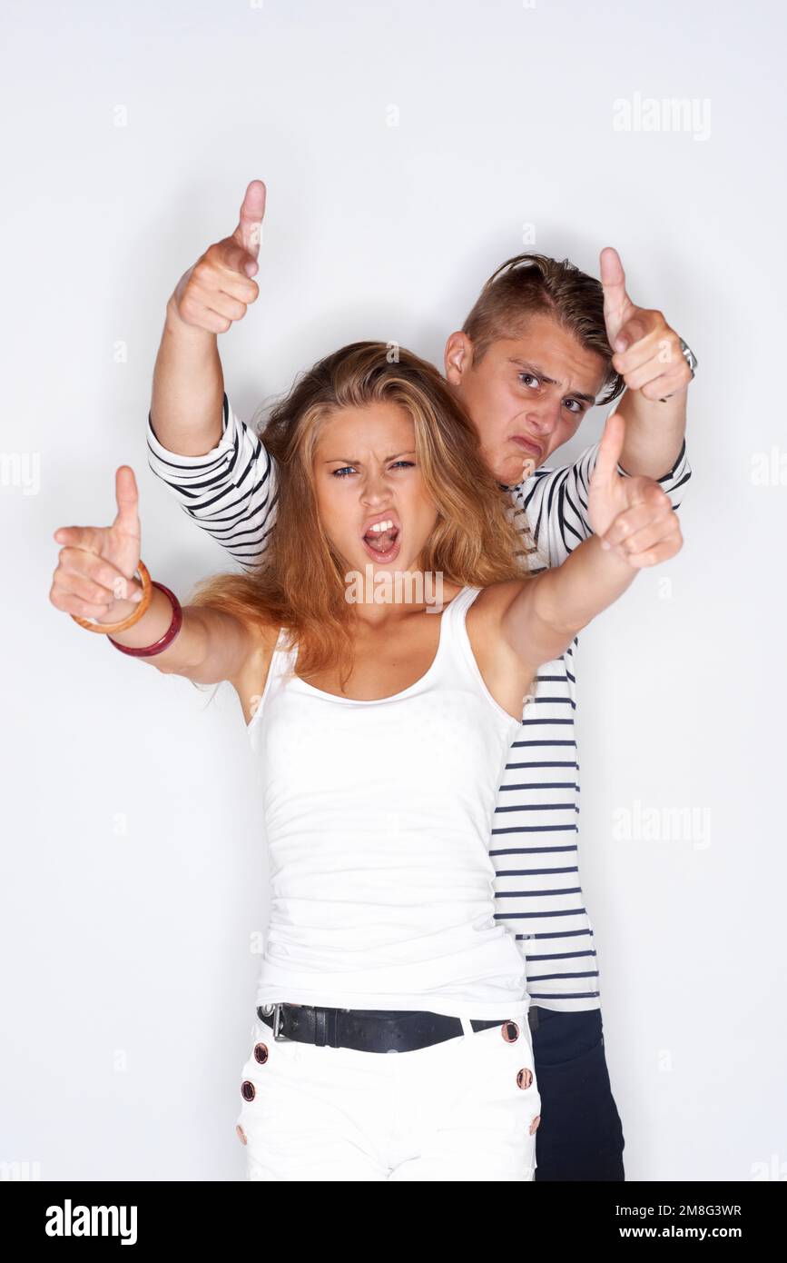 Rebell ohne Grund. Porträt eines Hipsters, männlich und weiblich, beide ziehen das Gesicht und halten die Daumen hoch. Stockfoto