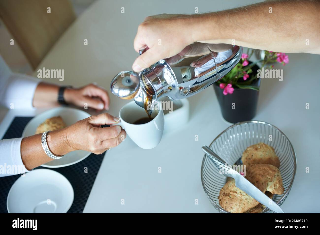 Dieses Gebräu riecht herrlich. Ein älterer Mann, der seiner Frau frischen Kaffee am Frühstückstisch einschenkt. Stockfoto