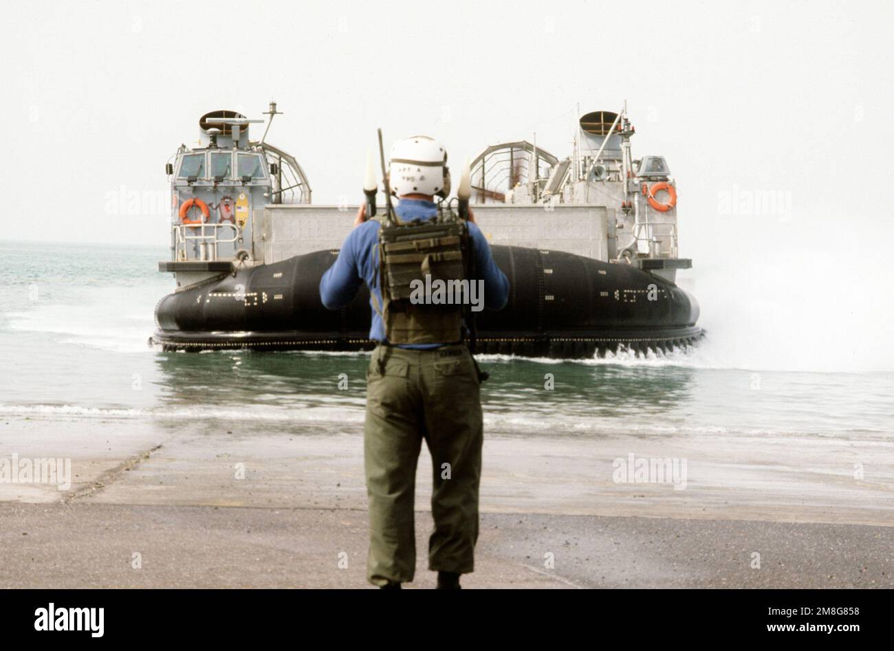 Ein Strandmeister leitet während der Übung Eager Mace 92-1, der ersten großen kombinierten US/kuwaitischen Übung seit dem Ende der Operation Desert Storm, ein luftgedämpftes Landungsfahrzeug (LCAC) der Assault Craft Unit 5 (ACU-5) an Land. Betreff Betrieb/Serie: EAGER MACE 92-1DESERT STURMLAND: Kuwait (KWT) Stockfoto