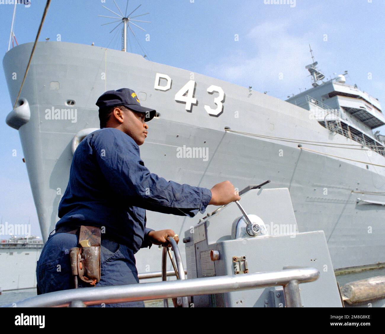 Ein Matrose manövriert ein kleines Boot vor dem Zerstörer USS CAPE COD (AD-43). Basis: Rota Land: Spanien (E) Stockfoto