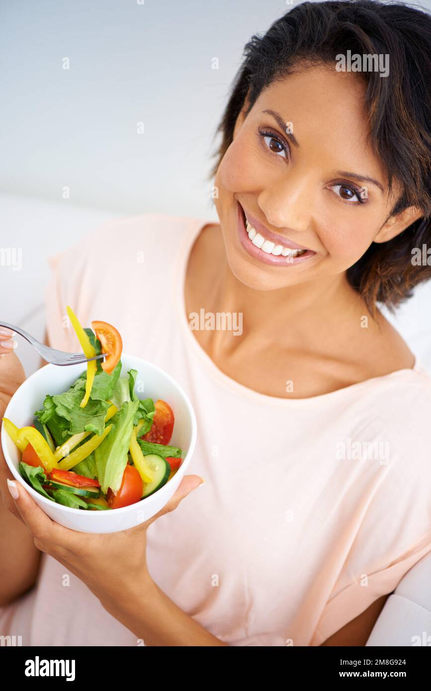 Bringen Sie Farbe in Ihre Gesundheit. Porträt einer jungen Frau, die zu Hause einen Salat genießt. Stockfoto
