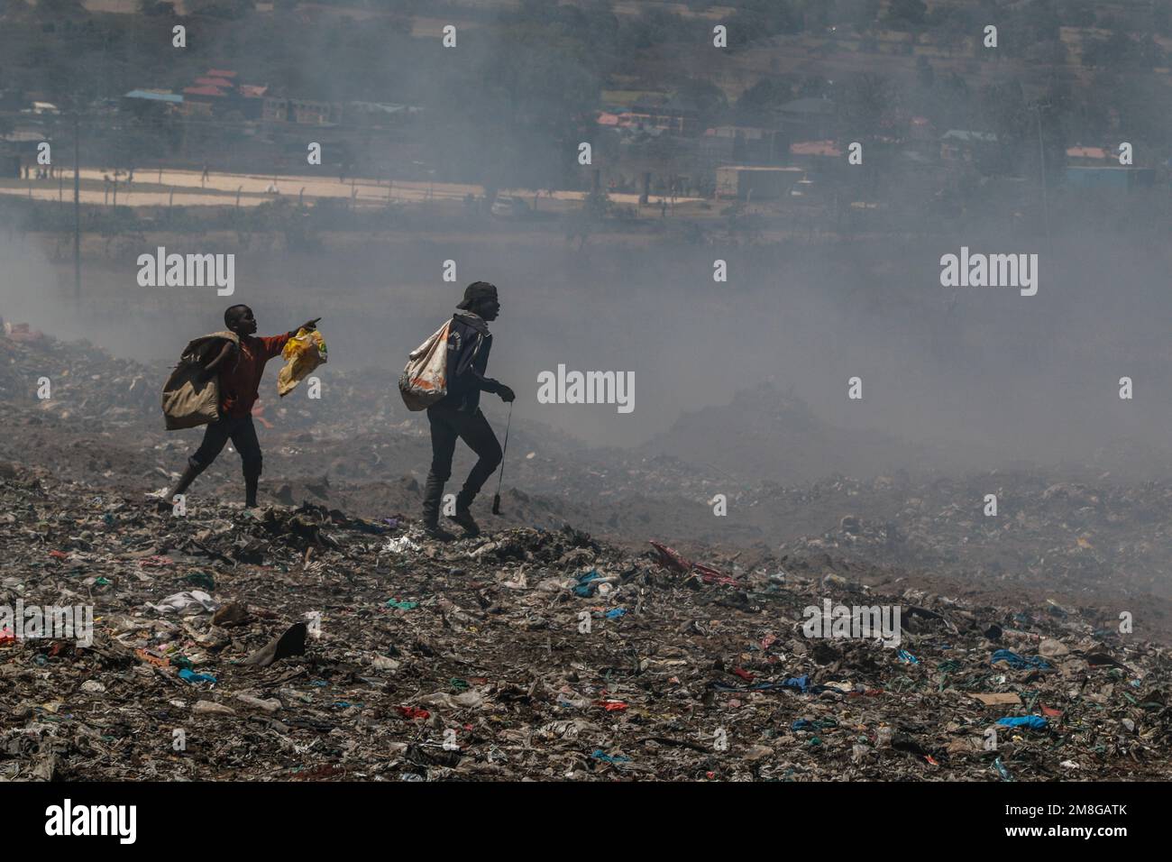Junge Abfallsammler sammeln Abfälle, um sie in starkem Rauch zu recyceln, indem sie Müll auf dem Hauptlagerplatz von Nakuru verbrennen. Da Abfälle selten getrennt und stark mit allen Arten von Abfall vermischt werden, kann das Verbrennen potenziell giftige Dämpfe erzeugen, die ein Problem für die öffentliche Gesundheit darstellen und auch zum Klimawandel beitragen können. Gemeinden, die in der Nähe von Mülldeponien arbeiten und leben, wo Müll offen verbrannt wird, sind dem Risiko von Atemwegserkrankungen und Krebs ausgesetzt. Frauen, die diesen Dämpfen ausgesetzt sind, können unter reproduktiven Gesundheitsproblemen leiden. Stockfoto