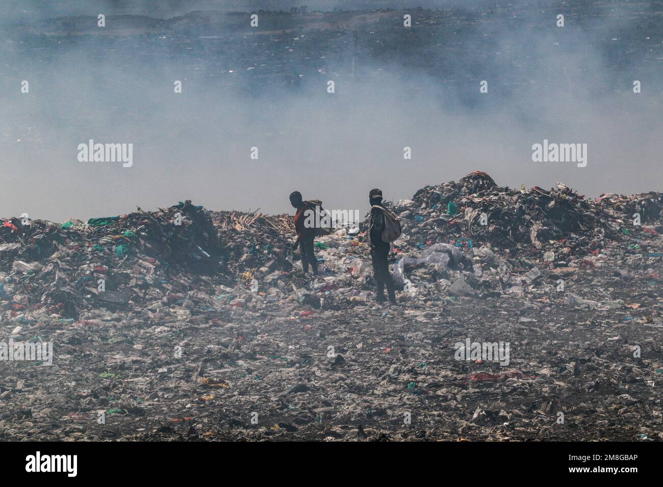 Müllsammler sammeln Abfälle, um sie in starkem Rauch zu recyceln, indem sie Müll auf dem Hauptlagerplatz von Nakuru verbrennen. Da Abfälle selten getrennt und stark mit allen Arten von Abfall vermischt werden, kann das Verbrennen potenziell giftige Dämpfe erzeugen, die ein Problem für die öffentliche Gesundheit darstellen und auch zum Klimawandel beitragen können. Gemeinden, die in der Nähe von Mülldeponien arbeiten und leben, wo Müll offen verbrannt wird, sind dem Risiko von Atemwegserkrankungen und Krebs ausgesetzt. Frauen, die diesen Dämpfen ausgesetzt sind, können unter reproduktiven Gesundheitsproblemen leiden. (Foto: James Wakibia/SOPA Images/Sipa USA) Stockfoto