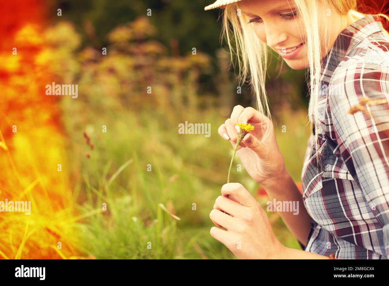 Genießen Sie die Geschenke der Natur. Schöne junge Frau auf einem Feld, die einen Strohfedora trägt. Stockfoto