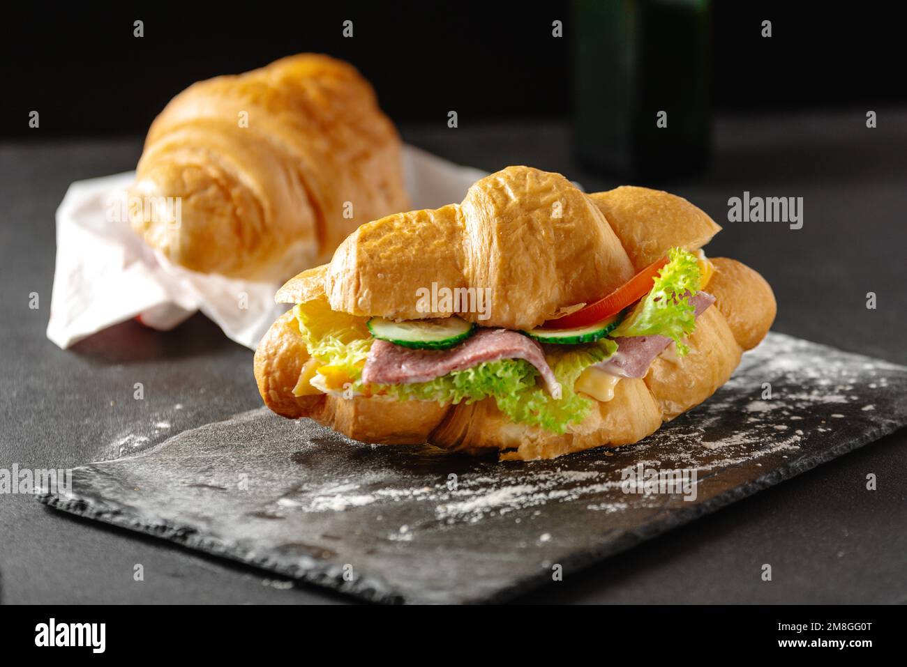 Köstliches Frühstück. Großes Croissant-Sandwich mit Wurst, Käse und Tomaten Stockfoto