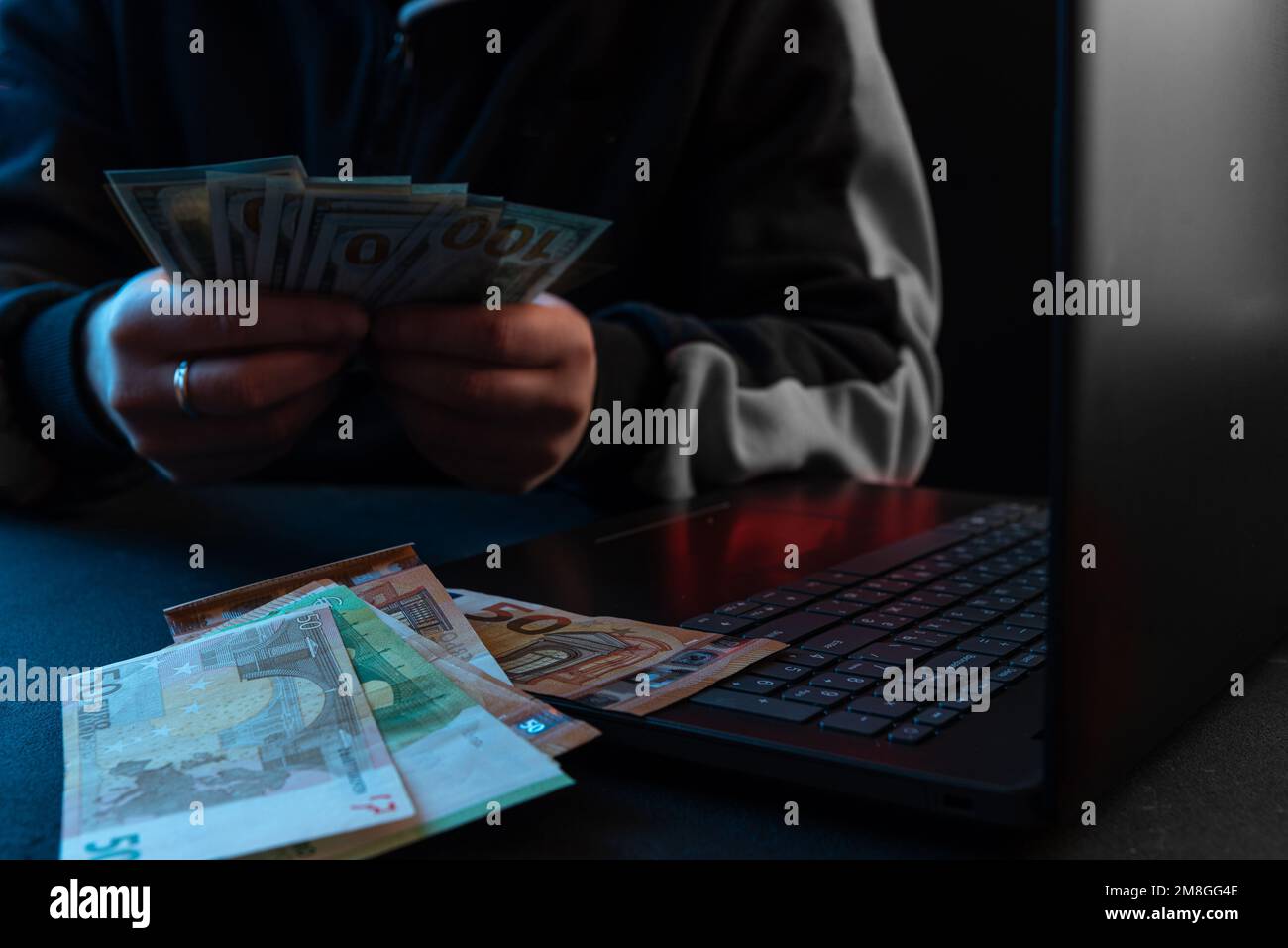 Ein Mann zählt das Geld vor seinem Laptop. Das Konzept, Geld im Internet zu verdienen Stockfoto