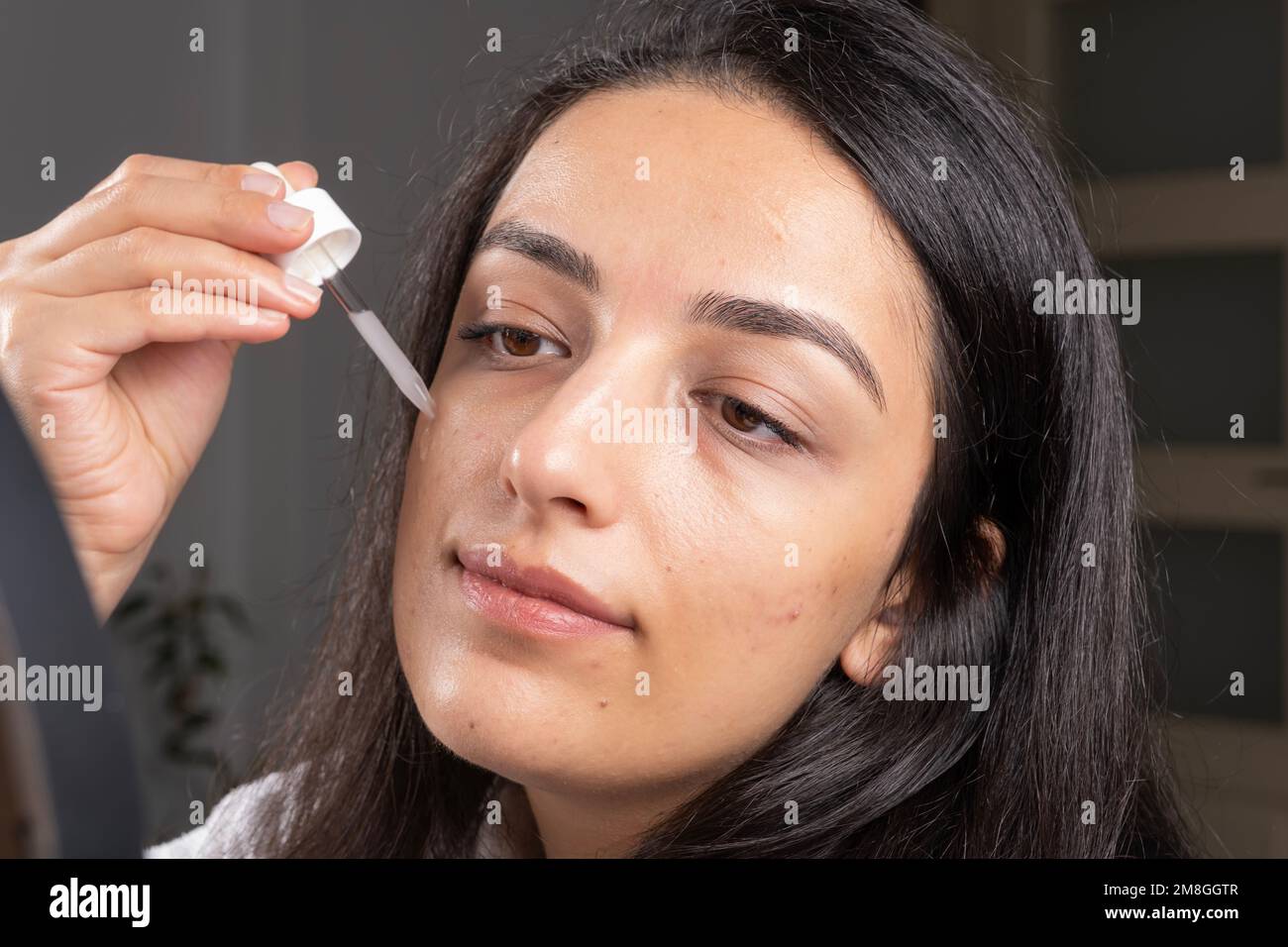 Frau in Tropfenhaltung und Anwendung von Gesichts-Hautpflegeserum. Akne-Behandlungskonzept-Ideenbild, Kopierraum. Anti-Alterung-Falten, natürliche Schönheit aus nächster Nähe Stockfoto