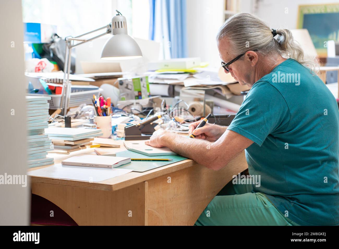 Kreativer reifer Mann, der mit einem Pyrographen arbeitet, der Holz verbrennt und Kunstwerke im Kunstatelier zu Hause macht. Stockfoto