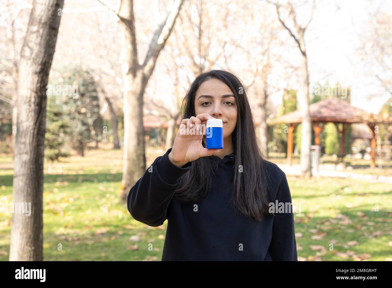 Zeigt Pillen-Flasche, weiße Brünette Frau steht draußen und zeigt Pillen-Flasche. Blaue leere oder leere Arzneimittelflasche. Stockfoto