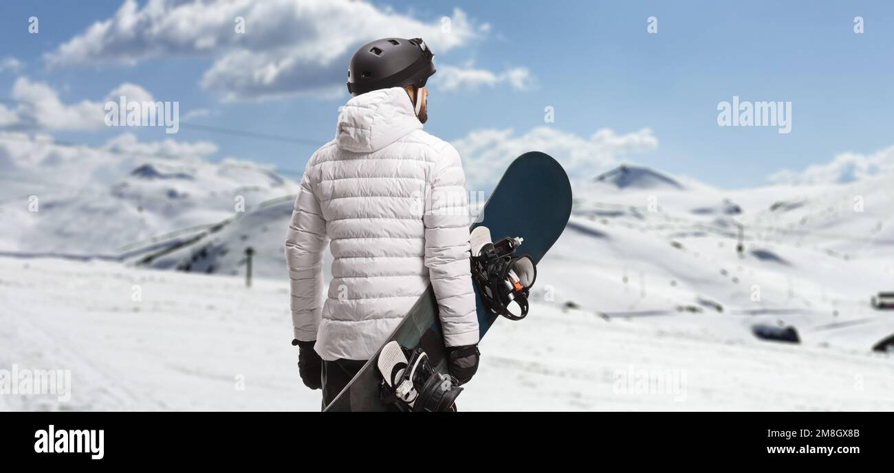 Rückansicht eines Mannes mit einem Snowboard und Blick auf einen Berg Stockfoto