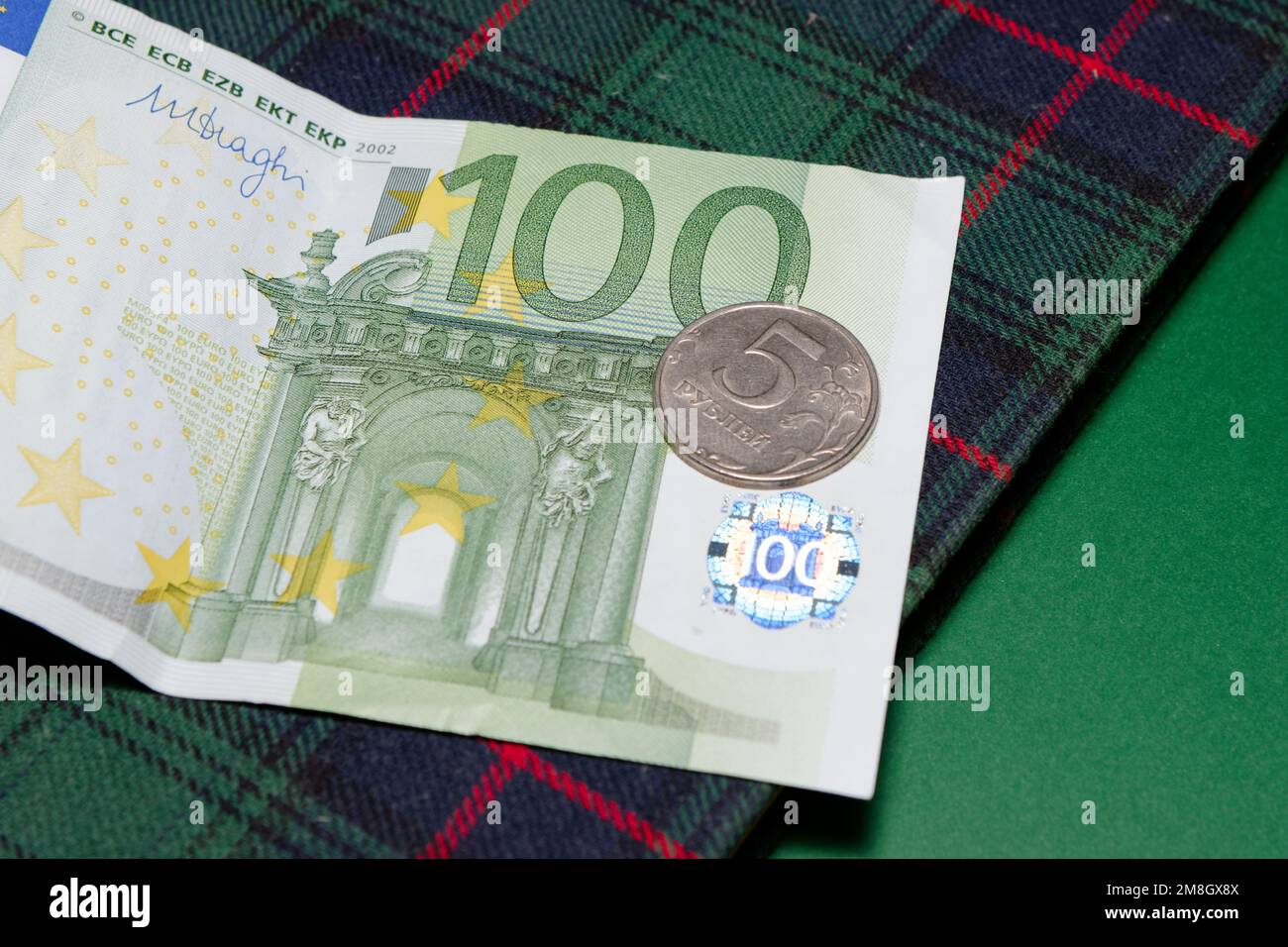 Eine Münze von 5 Rubel auf einem 100-Euro-Schein Stockfoto