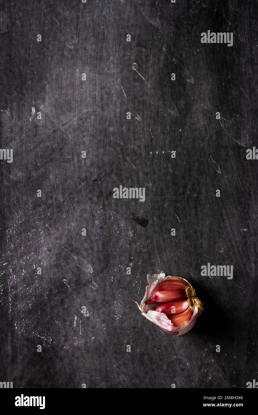 Frische Knoblauchzehen auf schwarzem Hintergrund. Flach verlegt. Draufsicht. Speisekonzept. Dunkle Stimmungsfotografie. Stockfoto