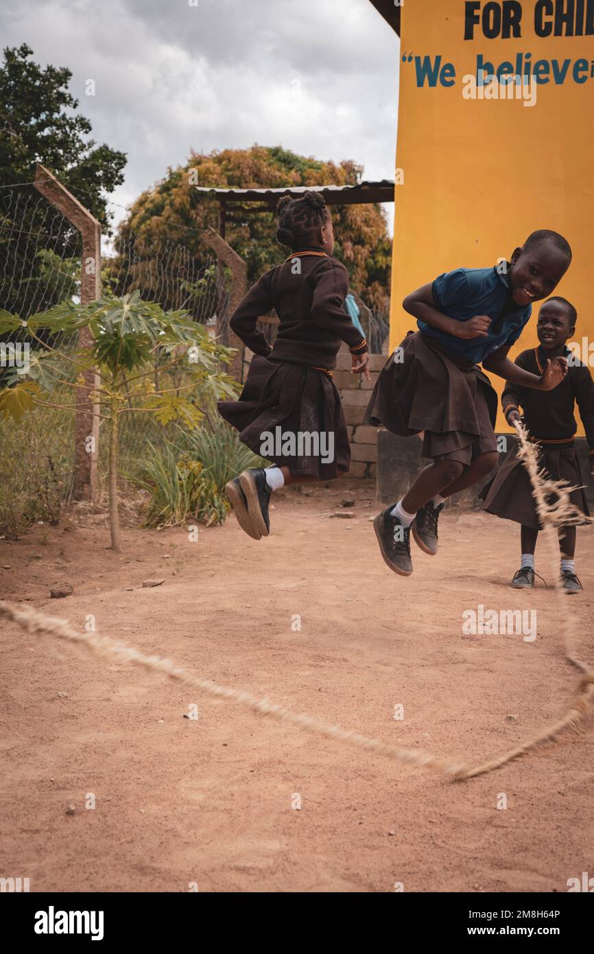 25. März 2022 - Mwanza, Tansania - Kinder, die auf dem Schulgelände spielen und Spaß haben. Laufen, Seil überspringen, Football spielen. Stockfoto