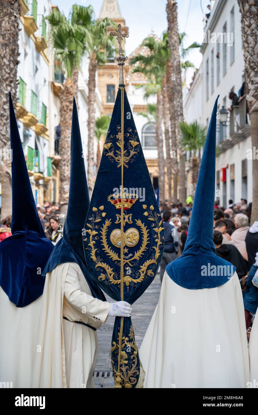 Menschen in traditionellen Kleidern, die einen capriote werdeten, oder Spitzhut bei einer Osterparade während der Heiligen Woche oder Semana Santa in Cadiz, Spanien Stockfoto