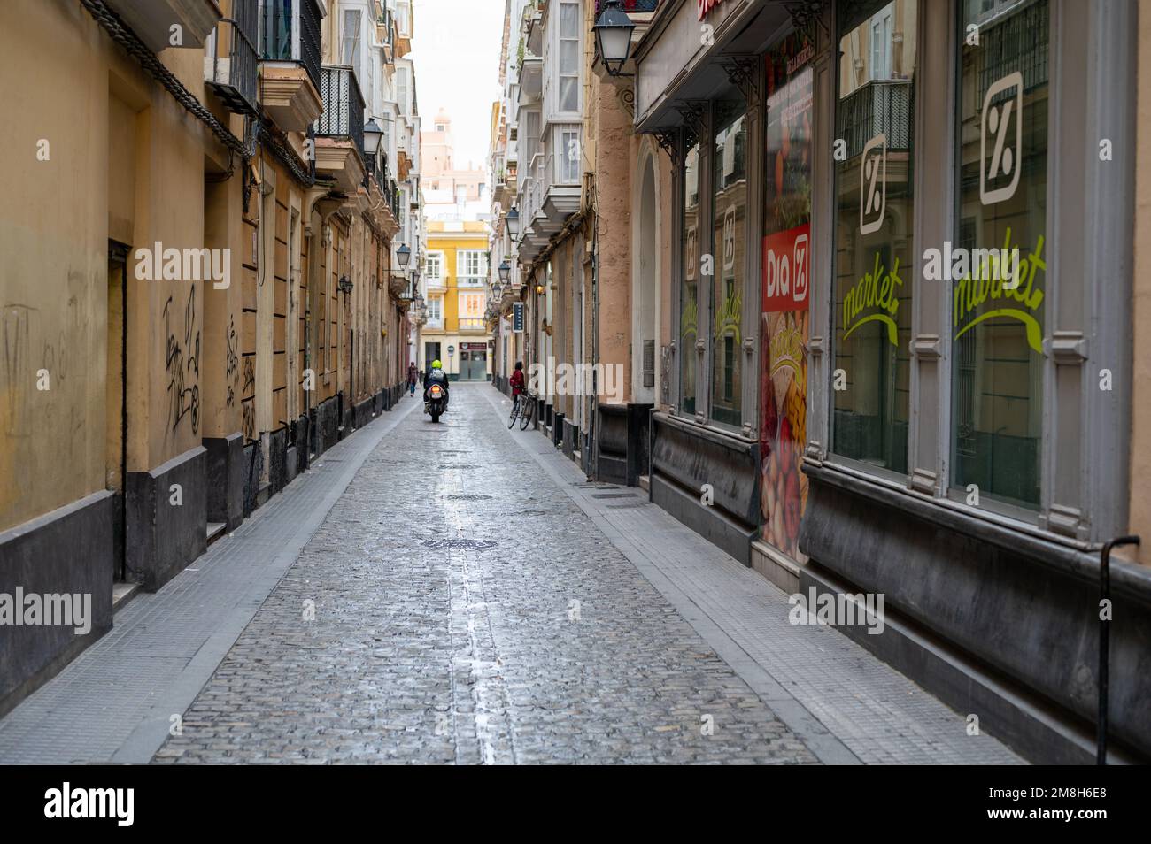 Eine enge Straße in der Stadt Cadiz Spanien mit Kopfsteinpflaster und Geschäften Stockfoto