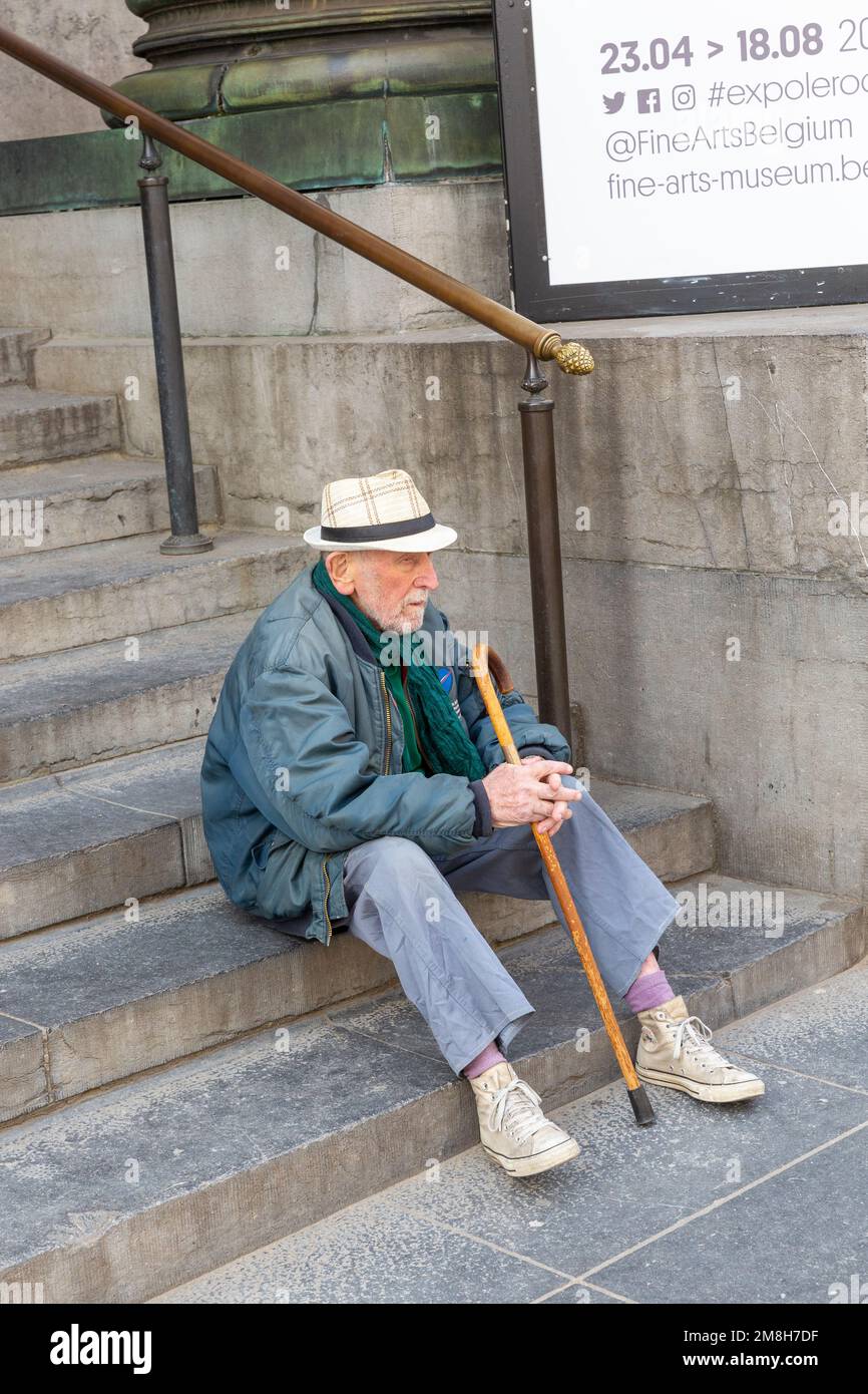 Ein Mann mit Stock und Strohhut, der auf den Stufen einer Treppe ruht. Brüssel. Stockfoto