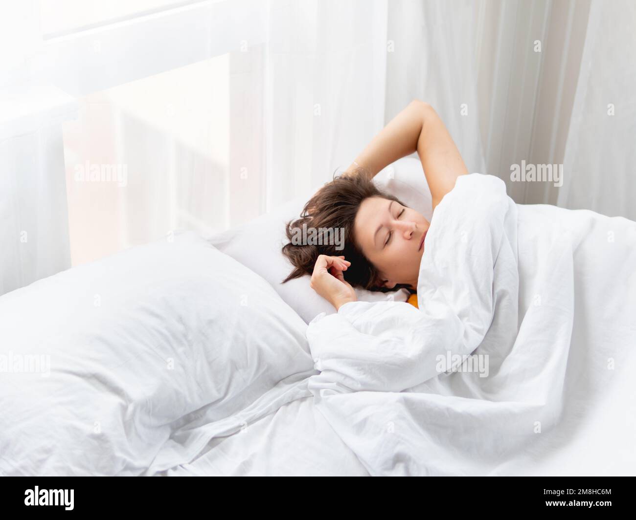 Kaukasische Frau schläft im Bett. Gesunder Schlaf auf weißer Bettwäsche. Morgen im gemütlichen Zuhause. Stockfoto