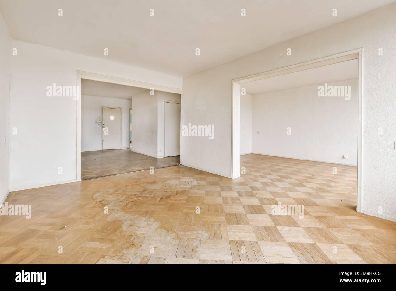 Ein leeres Zimmer mit weißen Wänden und Holzfußboden im mittleren Teil des Zimmers, es gibt keine Möbel Stockfoto