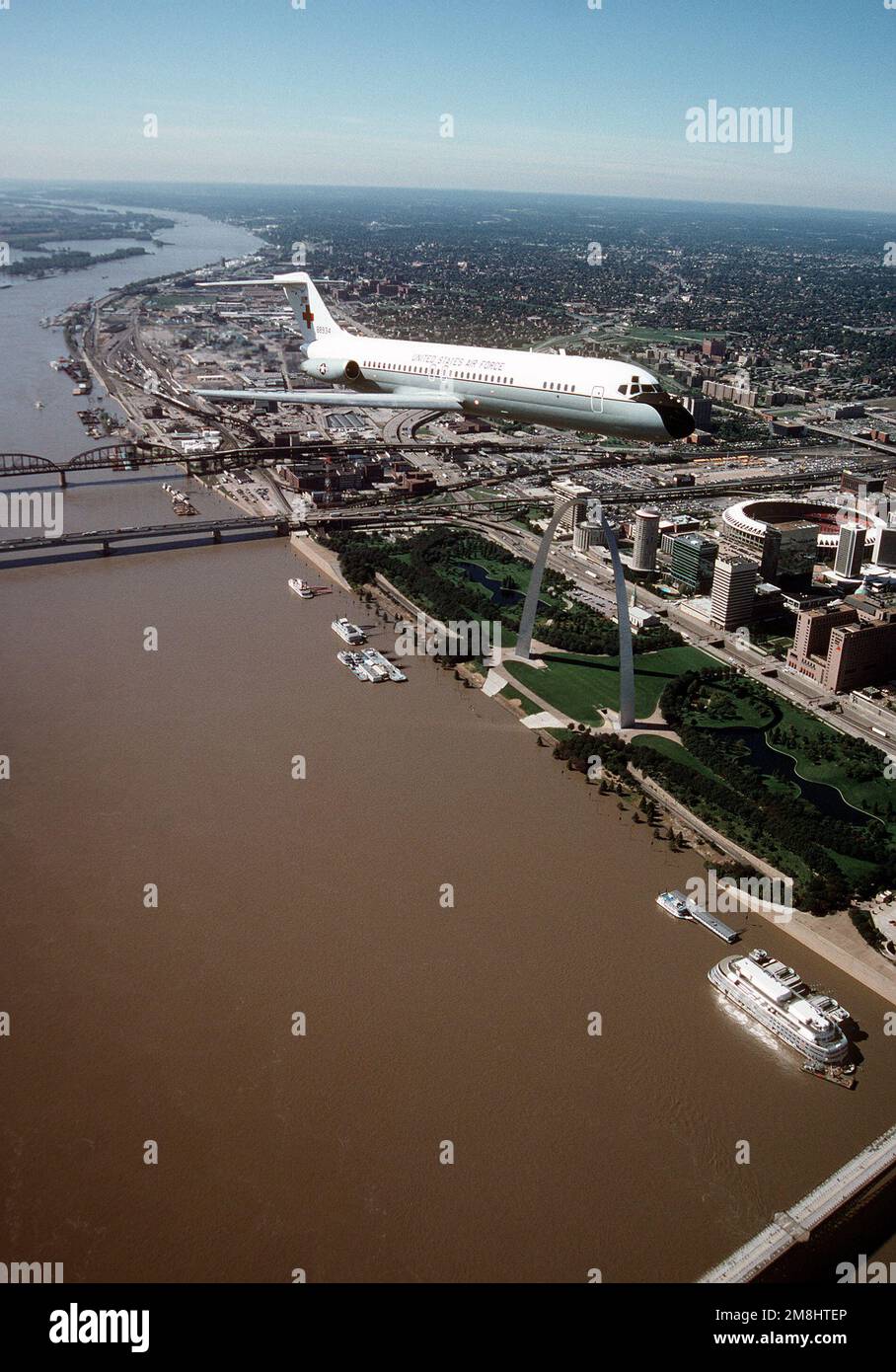 Ein Air-to-Air, dreiviertel Vorderansicht eines von McDonnell Douglas gebauten C-9A Nightingale-Flugzeugs während eines Fluges über die berühmte St. Louis Arch, am Ufer des Mississippi River und im Busch-Stadion. Die C-9A ist dem 375. Airlift Wing, Air Mobility Command, zugewiesen. Stützpunkt: Luftwaffenstützpunkt Scott Bundesstaat: Illinois (IL) Land: Vereinigte Staaten von Amerika (USA) Stockfoto