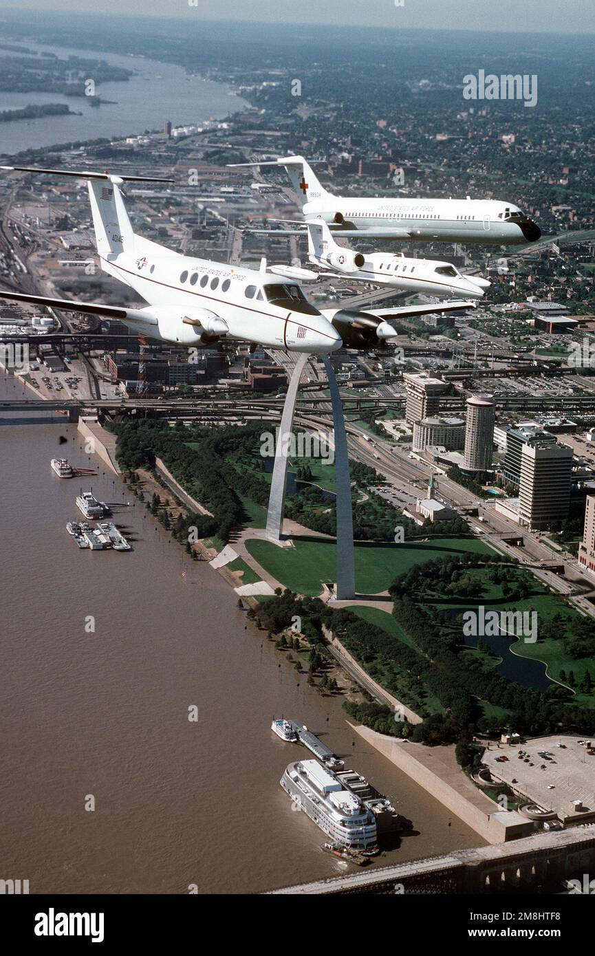 Eine Luft-zu-Luft-Vorderansicht eines Beech-Flugzeugs, das C-12F mit einem Lear Jet C-21A und einem von McDonnell Douglas gebauten C-9A Nightingale, das vom linken Flügel des C-12F abfliegt. Alle Flugzeuge sind vom 375. Luftwaffenflügel, Luftmobilitätskommando und fliegen über die St. Louis Arch, am Ufer des Mississippi River, und das Busch-Stadion während einer Trainingsmission. Stützpunkt: Luftwaffenstützpunkt Scott Bundesstaat: Illinois (IL) Land: Vereinigte Staaten von Amerika (USA) Stockfoto