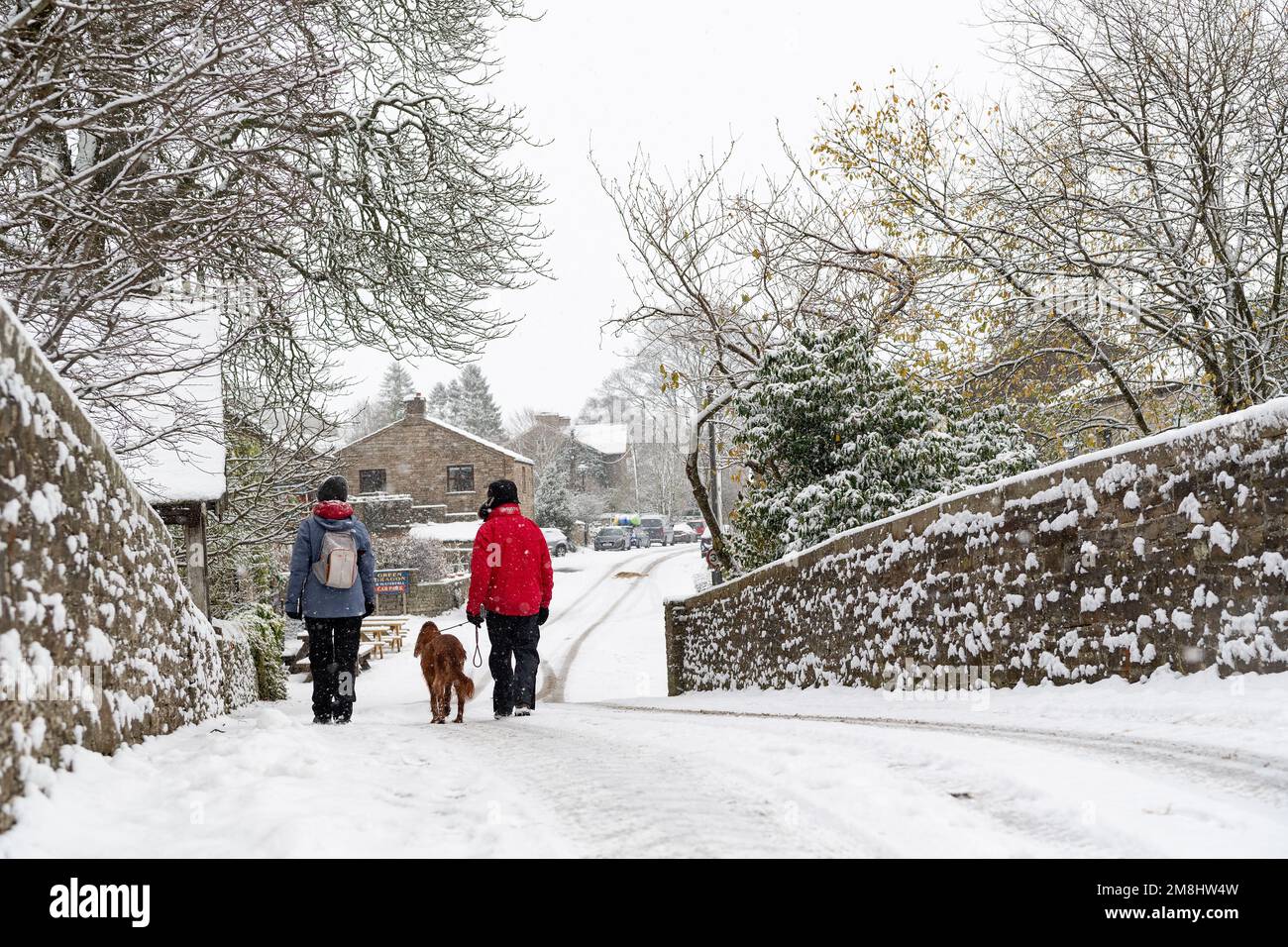 Spaziergänger mit einem Hund in Führung bei einem Spaziergang im Schnee in Hardrow in den Yorkshire Dales, Großbritannien Stockfoto