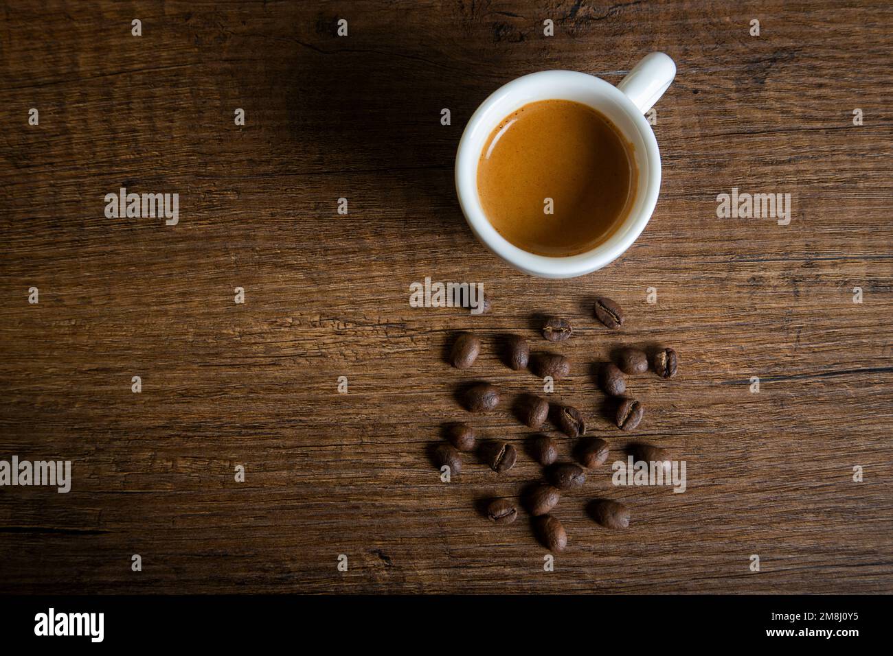 Weiße Tasse Espresso mit Kaffeebohnen auf einem Holztisch Stockfoto