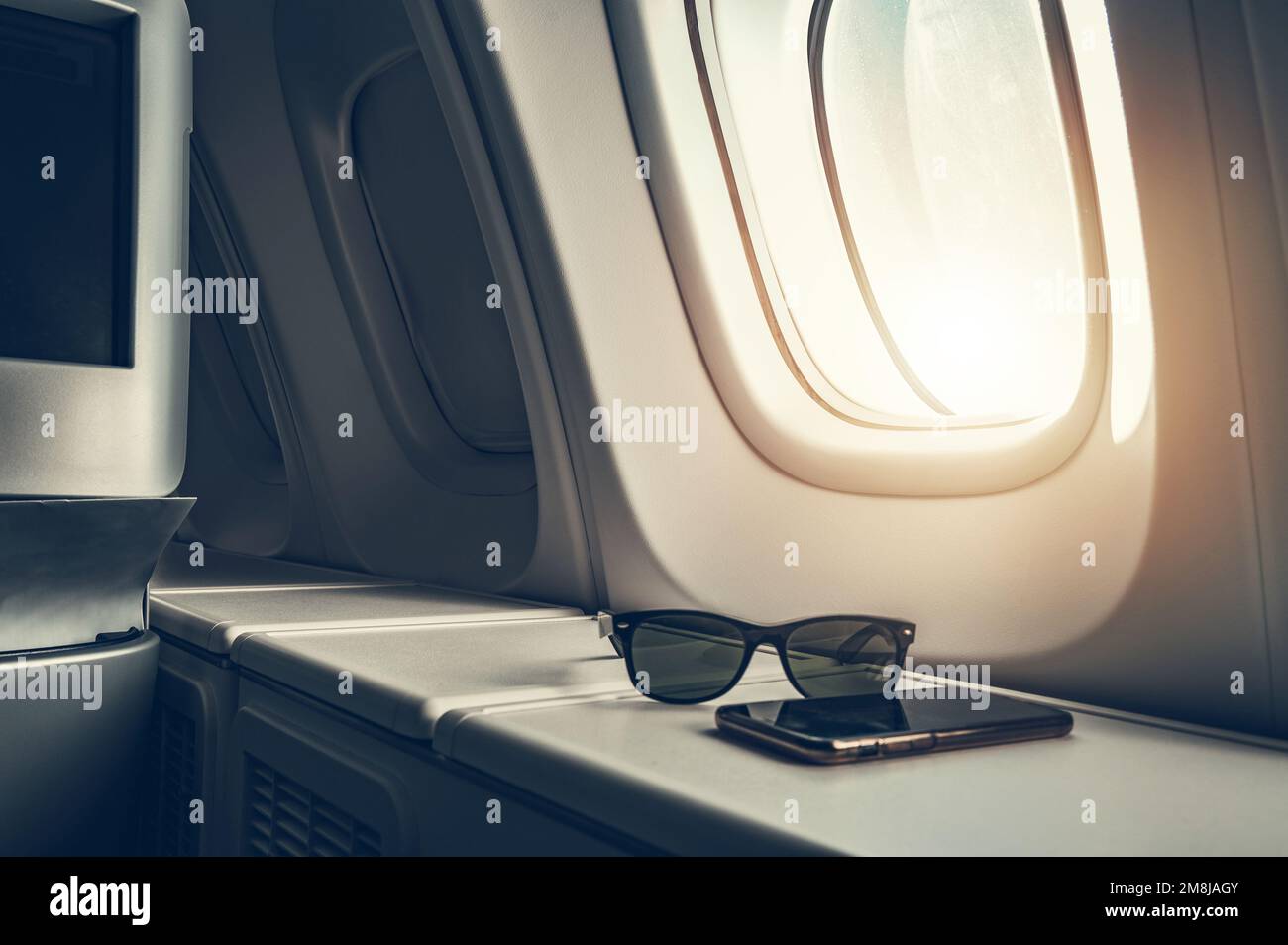 Flugkonzept der Business Class mit Sonnenbrille und Smartphone auf einem Tisch. Business und Vergnügen Thema Flugreisende. Stockfoto