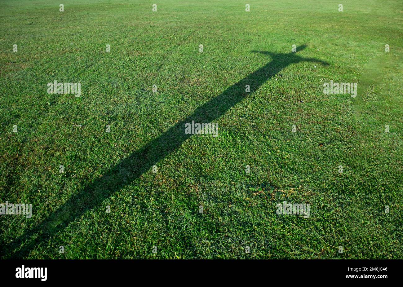 Silhouette des Menschen in Kreuzform auf grünem Gras Stockfoto