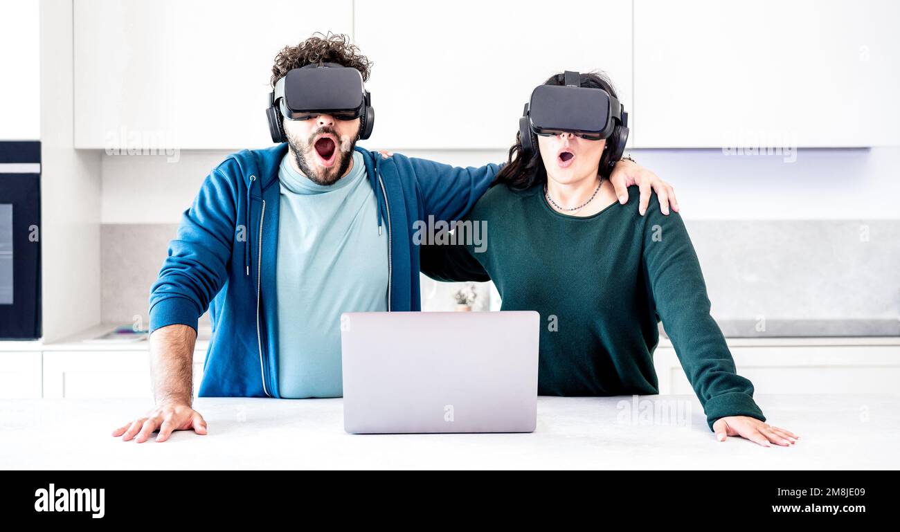 Millennial Couplr spielt mit VR-Brillen in der Küche – Virtuelle Realität und technisches Konzept mit engagierten Menschen, die Spaß mit der Headset-Brille haben Stockfoto